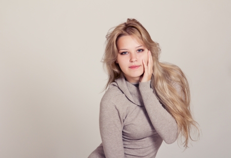 Beautiful young slim woman with long blond hair in beige dressの写真素材