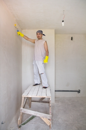Young man painting wall with painting rollerの写真素材