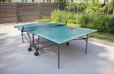Green ping-pong table and rackets outdoors