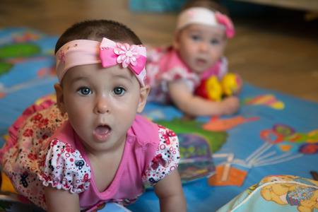 Surprised funny infant sisters, twin baby girls の写真素材