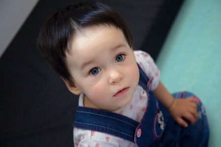 Cute serious one-year-old toddler closeup portrait - sweet sad little baby with beautiful grey eyes