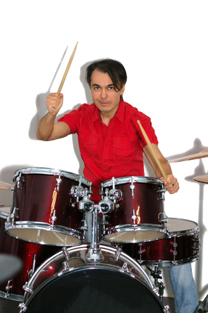 Middle aged drummer in red shirt with drumsticks in his hands playing drum set. Isolated on a white backgroundの写真素材