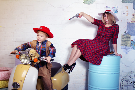 Mother and Son having fun. Studio image with scooter and barrels as a backgroundの写真素材
