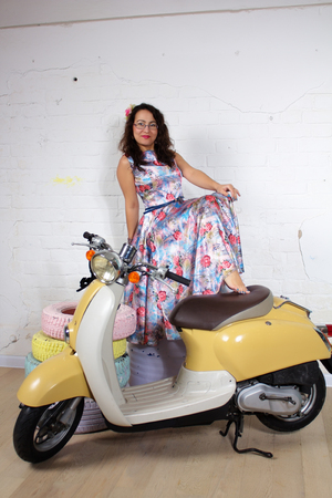 Studio portrait of a beautiful asian woman with a flower in her hair posing with motorbike barefeetの写真素材
