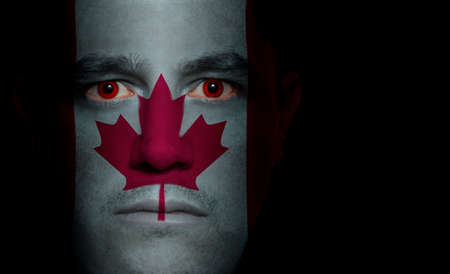 Canadian flag painted/projected onto a man's face.の写真素材