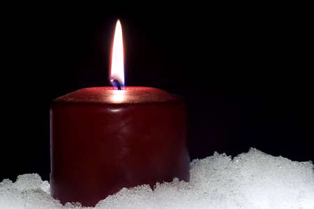 Red candle sitting in a base of snowの写真素材