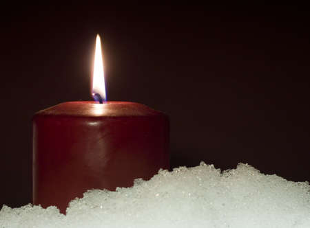 Red candle sitting in a base of snowの写真素材