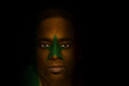 Man with Senegalese flag painted/projected onto his face.の写真素材