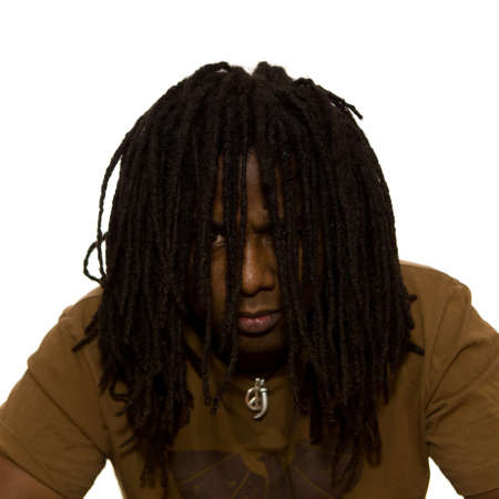 Serious African adult male with dreadlocks hanging in front of his face on a white background.の写真素材