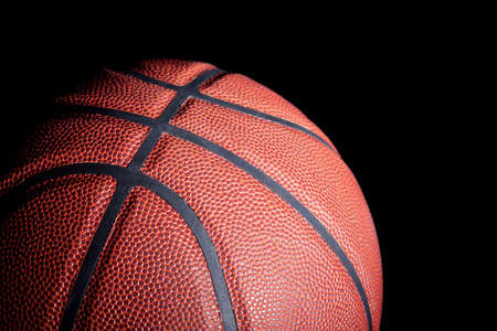 Close-up of a basketball with dramatic side lighting on a black background.の写真素材