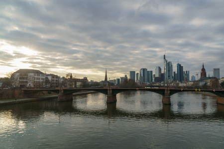 Stunning sunset view of the financial skyline in Frankfurt. Pictures were taken from the Floesserbruecke during blue hour in february. Thus the office rooms already have their lights on and having lots of light effects on the main river.の写真素材