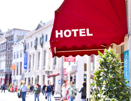 Building exterior of an ancient city hotel with red sun blind and white text. Selective focus with copy space.のeditorial素材