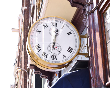 antique golden clock at a house facade. Antique watch shop in a historic city with elegant house...