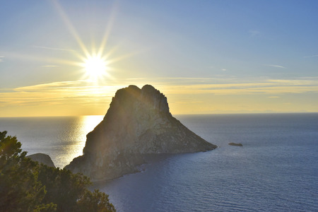 Sunset at Es Vedra, Ibiza Island. Sunbeam with lens flare behind the Isle of Es Vedra, magic rock of Ibiza.の写真素材