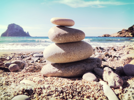Balanced stones on the beach. View to the magic rock es Vedra in the backgroundの写真素材