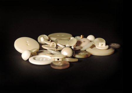 White sewing buttons, isolated on black background.