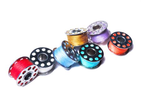 Sewing bobbins of various colors, isolated on white background.