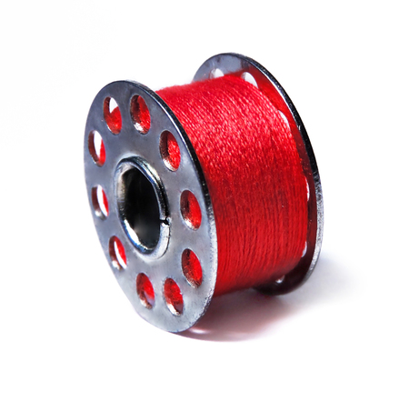 red thread on a sewing bobbin, isolated on white.の写真素材