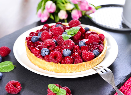 Delicious raspberry and blueberry cake, fruit tart with decorative tulip bouquet. Summer cake...