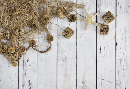 Fishing net or nautical vessel and starfish on wooden planks. Beach background or summer background with copy space.の写真素材