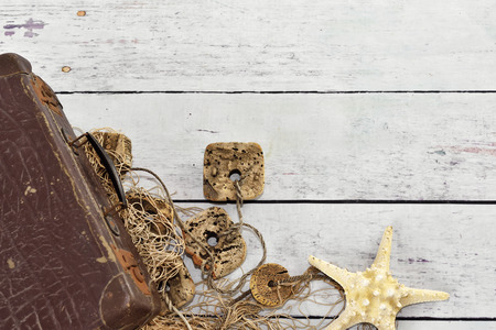Fishing net, suitcase and starfish on wooden planks. Beach background or summer background with copy space.の写真素材