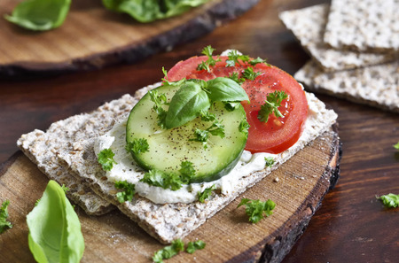 Healthy eating or dieting scene with crispbread and fresh tomatoes and cucumber. Wooden table, rustic scene.の写真素材