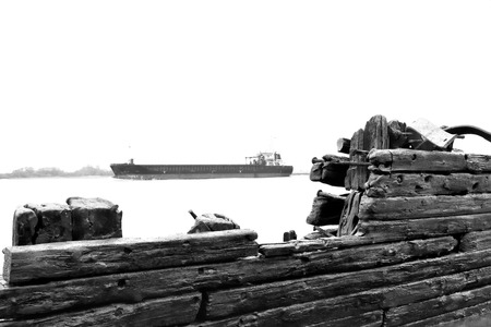 Old, beached shipwreck on the beach with weathered wood. Ancient ship wreckage and container ship. Beach scene. Freight shipping, Hamburg.の写真素材