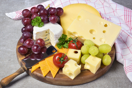 Delicious cheese plate with various sorts of cheese like Emmentaler, gouda and brie. Gourmet cheese on a wooden cutting board.の写真素材