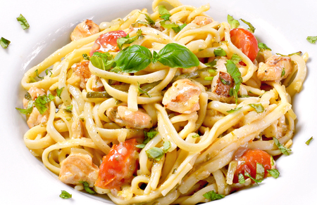Delicious salmon pasta dish, tagliatelle or linguine noodles. High angle view of fresh spaghetti with herbs and cherry tomatoes.の写真素材