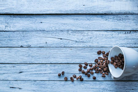 Coffee beans and coffee cups are placed on a white wooden floor.の写真素材