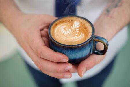 Barista holding hot coffee with latte artの写真素材