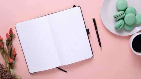 Pistachio macaroons on top of a plate with-assorted flowers on a flat lay top view pastel light pink backgroundの写真素材