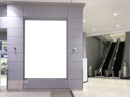 Large portrait advertisement space mock up with blurred escalator on the side inside a retail...