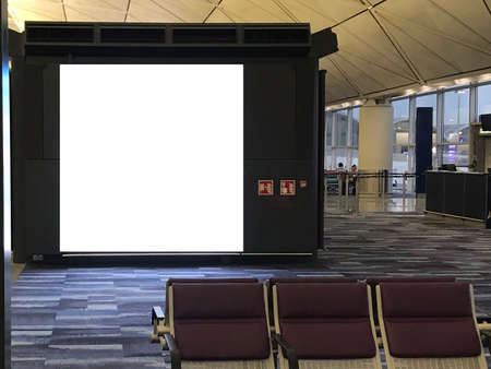 Large advertisement space light box inside an airport's departure waiting area with empty chairs