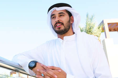 Happy handsome Arabian guy looking far and smiling wearing kandoora dishdasha