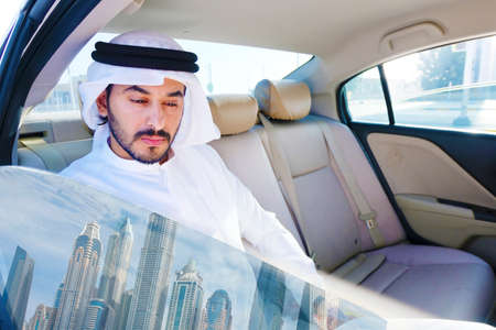 Arab UAE rich man inside a luxury car with reflection of Dubai cityspace from the windowの写真素材