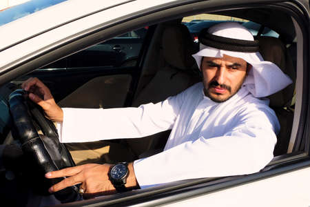 Middle Eastern Arab man driving a car  wearing traditional UAE menswearの写真素材