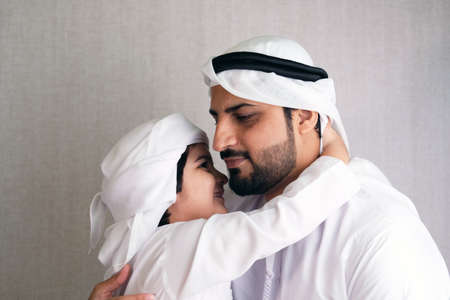 Arab parent teaching son on Kandura Middle Easter father with his Arabic young boy doing home...