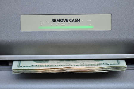American cash being dispensed from a bank automated teller maching, or ATM