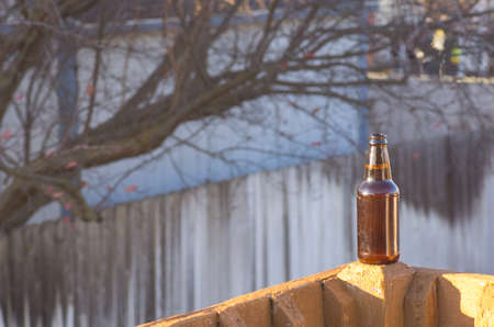 Bottle of beer on rail with tree in backgroundの写真素材