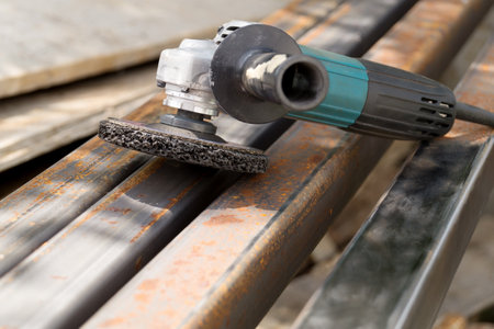Not new electric angle grinder tool lies on a rust metal square tube. Rust removal with wire brush from a metal surfaceの写真素材