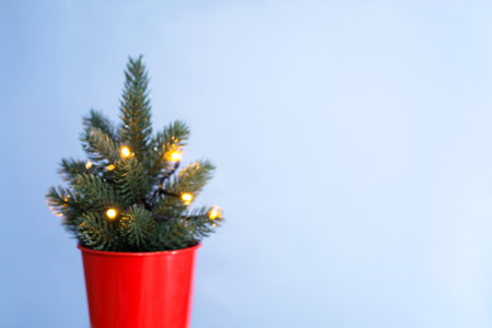 Blurred Christmas background. Christmas tree in a red bucket with garland with lights on blue background, festive gold bokeh. Christmas and Winter concept. Copy spaceの写真素材