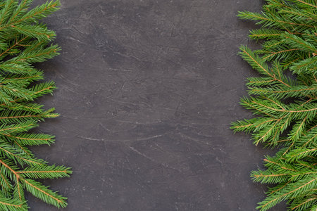 Christmas background with Christmas tree branches on a dark textured background. Frame of fir branches. New Year border. Top view with copy spaceの写真素材