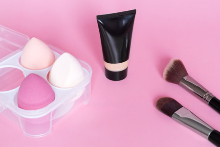 Makeup foundation, make up sponge and brush on pink background. Cosmetic tool concept. Beauty accessories.の写真素材