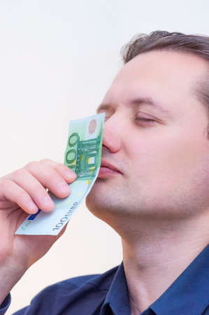 Portrait of young Caucasian Ethnicity man smelling money one hundred euros banknote with closed eyesの写真素材