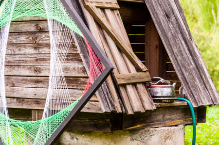 Traditional Lithuanian village with a bit of new waves and style. Old concrete well with wooden roof, metal kettle and psychedelic rhombus decoration on it.の写真素材