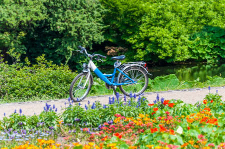 Amazing parks of Bremen, Germany. On this shot you can see a blue bicycle on park's lane surrounded by blooming flowersの写真素材