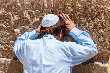 Jerusalem, Israel: Secular Jewish man praying near the stones of the Western Wall full of written notes to God. Western Wall is one of the major ancient Jewish relics.の写真素材