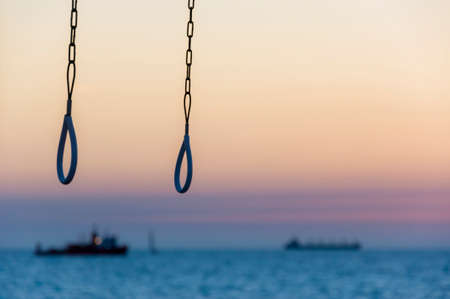 Sunset above Mediterranean sea coast with beach shower handles and ships on backgroundの写真素材