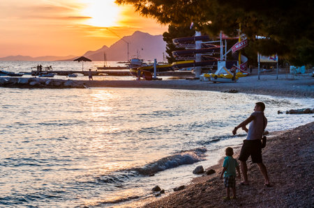 Makarska, Ð¡roatia - June 21, 2014: Summer portrait of Makarska beach at sunset. Stone skipping...